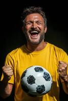 Cheerful man in yellow shirt celebrating with a soccer ball, showcasing enthusiasm and joy photo