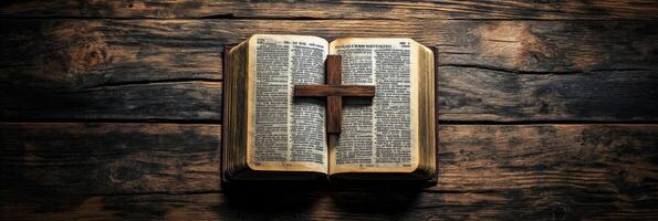 An open Bible resting on a wooden surface with a cross illuminated by soft light photo