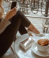Relaxing in a cafe with a smartphone, coffee, and croissant during a sunny afternoon photo