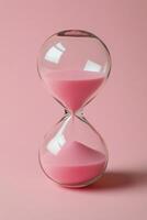 Elegant hourglass with pink sand on a vibrant pink backdrop, emphasizing the passage of time photo