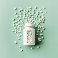 Brown glass bottle filled with tablets surrounded by scattered white pills on a green background photo