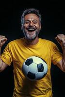 Cheerful man in yellow shirt celebrating with a soccer ball, showcasing enthusiasm and joy photo