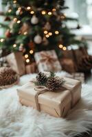 A wrapped gift with pine cones rests on a fluffy rug by a decorated Christmas tree photo