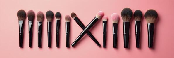 A set of makeup brushes in varying shapes on a pink background photo