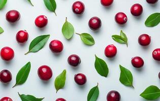 Fresh cranberries and green leaves arranged on a light background in an artistic display photo