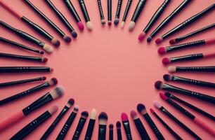 A colorful arrangement of makeup brushes and sponges on a vibrant pink background photo