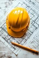 Yellow safety helmet rests on blueprints with a pencil on a construction table photo