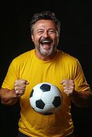 Cheerful man in yellow shirt celebrating with a soccer ball, showcasing enthusiasm and joy photo