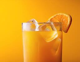 A glass of orange juice with ice, on a bright yellow background photo