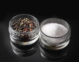 Sea salt and pepper in a container, on a black background photo