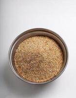 Small container containing quinoa grains, placed in the center of a white background photo
