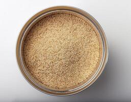 Small container containing quinoa grains, placed in the center of a white background photo