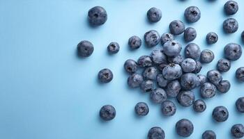 A handful of blueberries are scattered on a light blue background photo