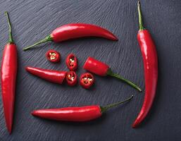 Red chili peppers arranged on a dark slate background photo