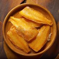 Dried fish in a wooden bowl on a table photo
