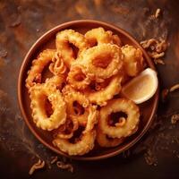 Fried squid rings on a plate with a lemon wedge photo