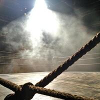boxing ring stands illuminated by powerful spotlights with smoke rising from the corners. Worn ropes frame the mat beneath low key lighting heightening the dramatic ambiance. photo