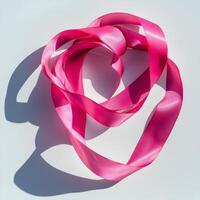 spiraled gymnastic ribbon in bright pink is beautifully arranged on a white surface featuring smooth texture and soft shadows under bright studio lighting. photo
