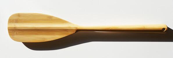 canoe paddle rests on a white surface showcasing its sleek blade shape and sturdy handle grip under bright lighting accompanied by soft shadows. photo