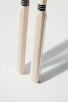 composition features a cricket wicket with bails placed on a clean white backdrop showcasing the intricate wood grain and gentle shadows created by bright lighting. photo