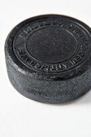 close up shot highlights the detailed surface of a hockey puck against a bright white background emphasizing its texture and embossed logo. photo