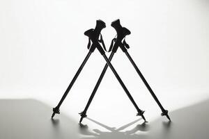 pair of ski poles are artistically crossed highlighting their grips and tips on a stark white background. Soft shadows create a minimalist aesthetic in natural midday lighting. photo