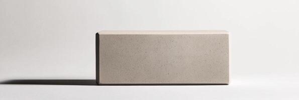 minimalist yoga block sits on a white background highlighting its textured surface and embossed logo while soft shadows fall below. The bright studio lighting enhances its design. photo