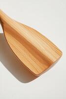 composition showcases a rowing oar with intricate blade and handle details against a white backdrop. The soft shadows and midday light enhance the natural wood texture. photo