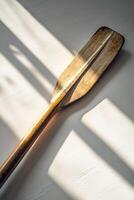 rowing oar is laid flat against a white background highlighting intricate details of the blade and handle. Soft shadows enhance the midday lighting creating a realistic aesthetic. photo