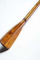 beautifully crafted wooden rowing oar is positioned flat against a white background highlighting intricate details of the blade and handle with soft shadows adding depth under midday lighting. photo
