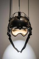 stylish ski helmet features a visor and attached goggles showcasing intricate straps and shadows. The minimalist design emphasizes winter sports readiness in a bright studio setting. photo