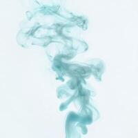 Soft turquoise tendrils of smoke swirl and rise softly, creating an enchanting display against a pristine white background, evoking serenity and calmness in every gentle curve. photo