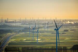 Aerial View on Waasland rural area mixed with wind turbines and harbor of Antwerp in the background during sunrise photo