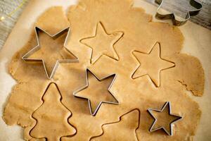 Top view of raw dough for cookies, cookie cutters and festive decoration on wooden table. photo