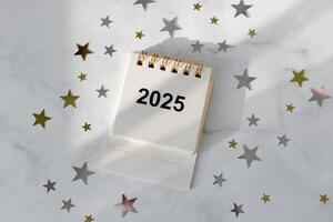 Desk calendar for 2025 on the table with sparkles shape of stars. Planning of new year concept. Flat lay. photo