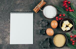 Christmas Recipe Menu Concept. Ingredients for cooking christmas baking and empty white paper notebook on brown stone background. Top view with copy space, mockup concept photo