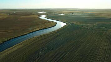An aerial view of a river flowing through a wide open field video