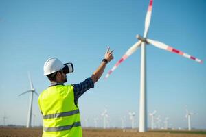 construction worker with outfit wearing VR headset with wind turbine in background photo