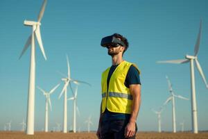 construction worker with outfit wearing VR headset with wind turbine in background photo