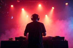 D.J. man standing in concert hall with smoke and colorful light enjoy music festival photo