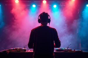 D.J. man standing in concert hall with smoke and colorful light enjoy music festival photo