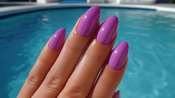A well-manicured hand with glossy violet nail polish photo
