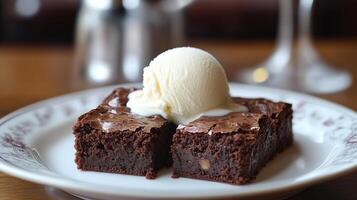 Brownies served with vanilla ice cream melting on top, on a white plate photo