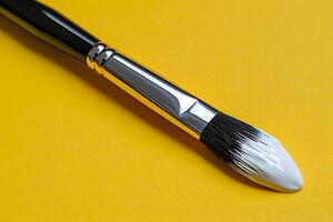 Artistic Paintbrush with White Paint on Bright Yellow Background for Creative Design Projects photo