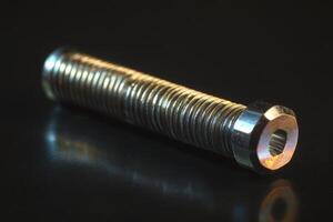 A screw with a nut on top of a black surface photo
