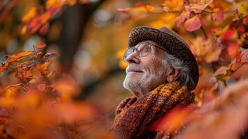An old man wearing a hat and scarf looking up at the leaves photo