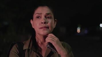 Captured in a close-up shot, a woman appears deep in thought as she looks around and touches her chin, her expression revealing anticipation and worry while she waits for a message or call video