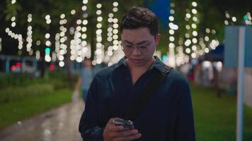 Asian man wearing glasses reading a message on his phone and feeling uneasy, stressed employee walking home showing negative emotions, unsuccessful business negotiation. video