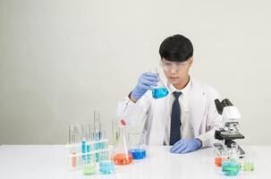Man asian student education learning scientist wearing doctor gown in lab looking hand at chemist. caused by mixing reagents in scientific research laboratories with test tubes and microscope on table photo