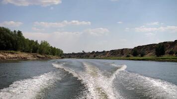 Boat wake on a river surrounded by trees and cliffs video
